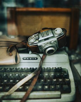Close-up of a vintage camera and typewriter on a wooden surface, showcasing classic technology.