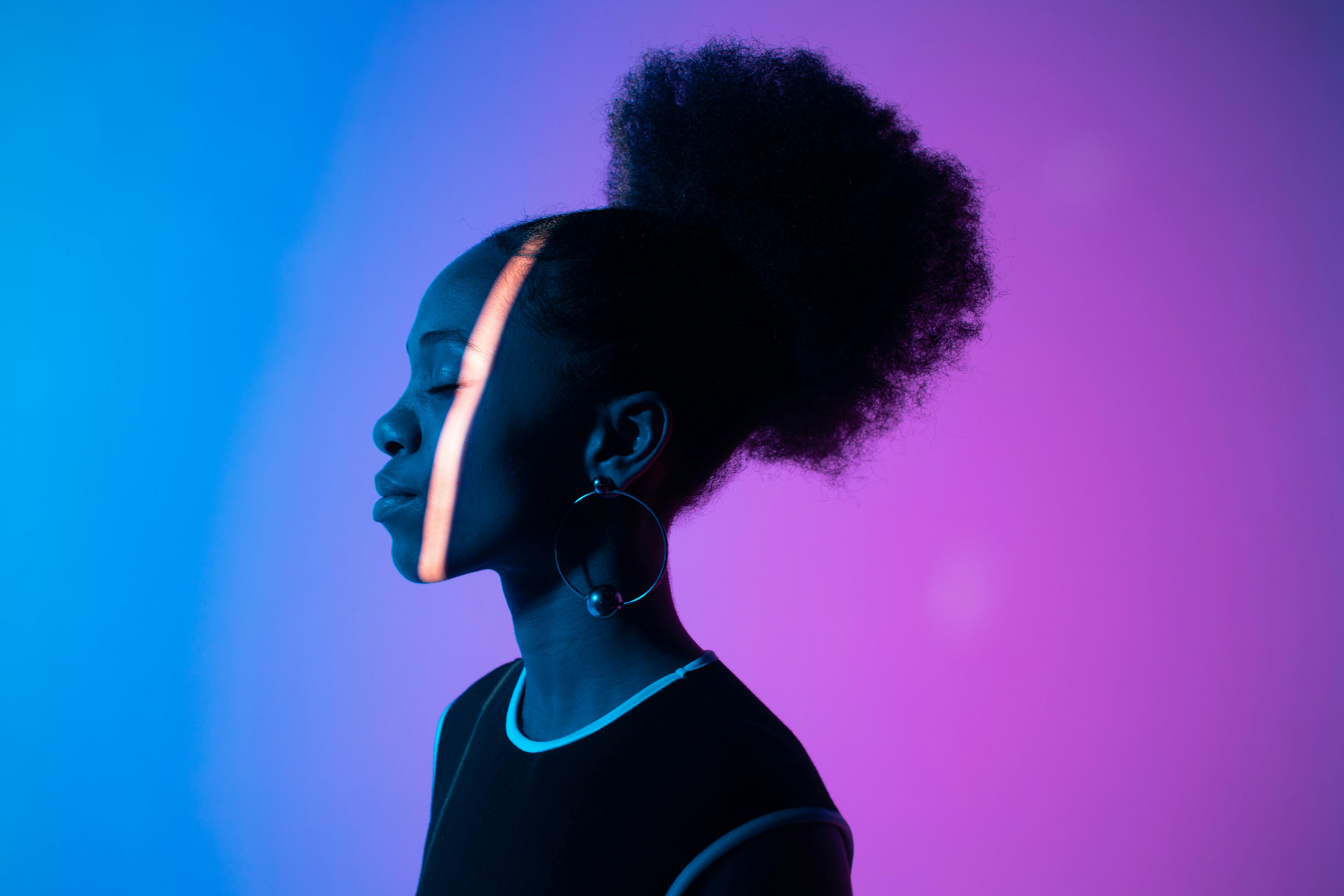 Creative studio portrait of a woman in neon lighting with a colorful background.