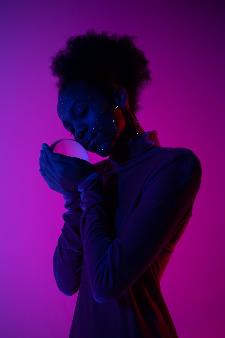 Woman Holding Glass Orb In Hands On Purple Back