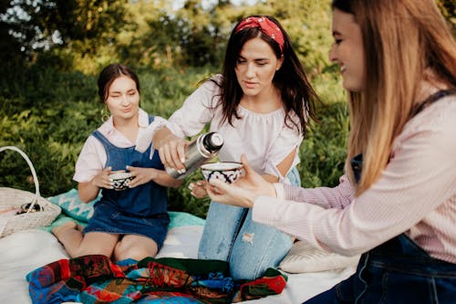 Women Pouring Tea from Thermos on Picnic