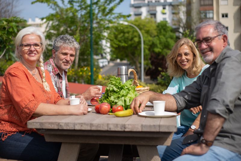 A group of seniors enjoying a sunny outdoor picnic, socializing and smiling