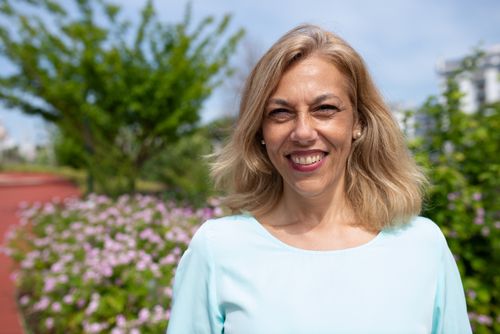 Free Cheerful adult woman with blonde hair smiling outdoors in a sunny garden setting. Stock Photo