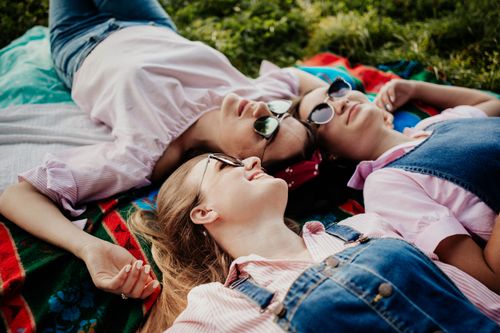 Free Three women enjoying a sunny day relaxing on a picnic blanket in the park. Stock Photo