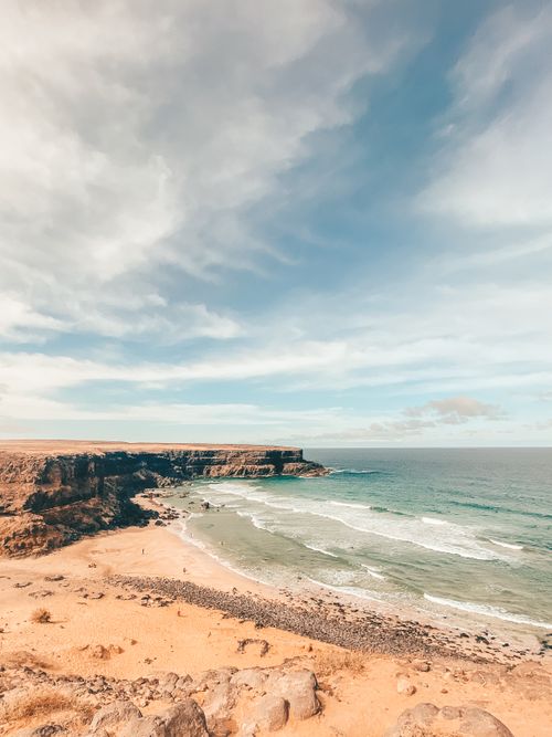 Free Explore the serene coastal beauty of Fuerteventura with sandy shores and ocean waves under a vast sky. Stock Photo