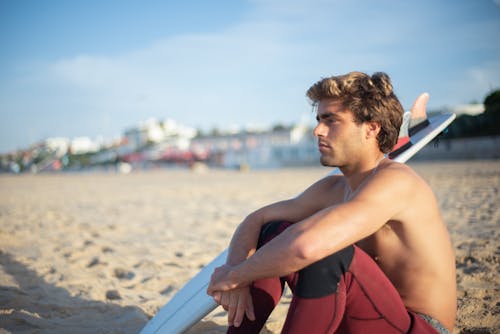 A Surfer Sitting on the Shore 