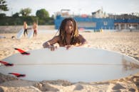 一个长着辫子的非裔美国人在葡萄牙的沙滩上拿着冲浪板