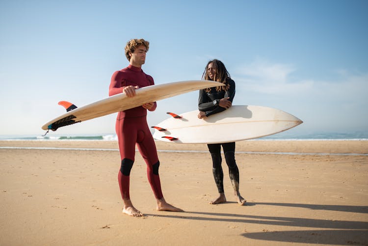 Men In Wetsuits Carrying Their Surfboards