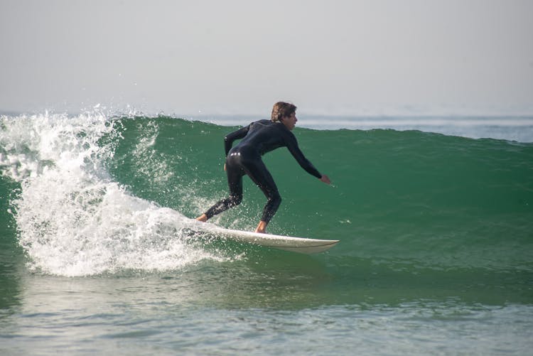 A Man In Wetsuit Doing Surfing