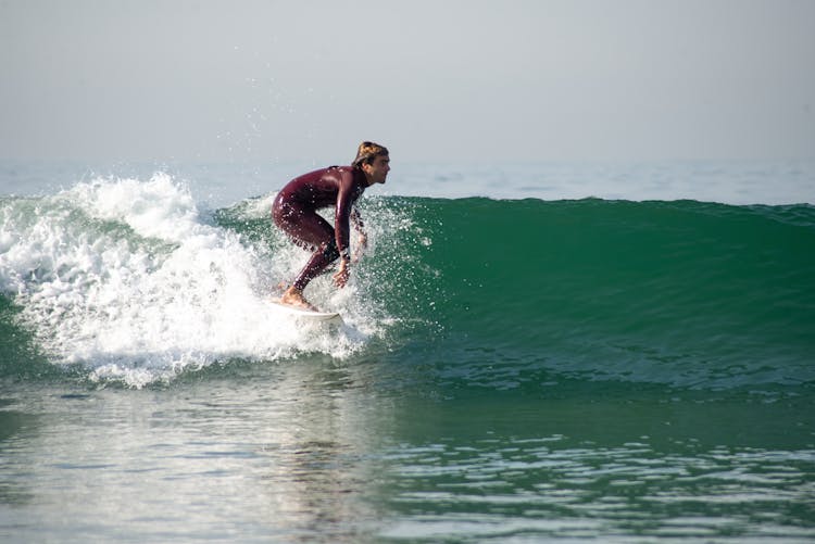 A Man Wearing A Surfer Rash Guard Surfing In A Beach Wave