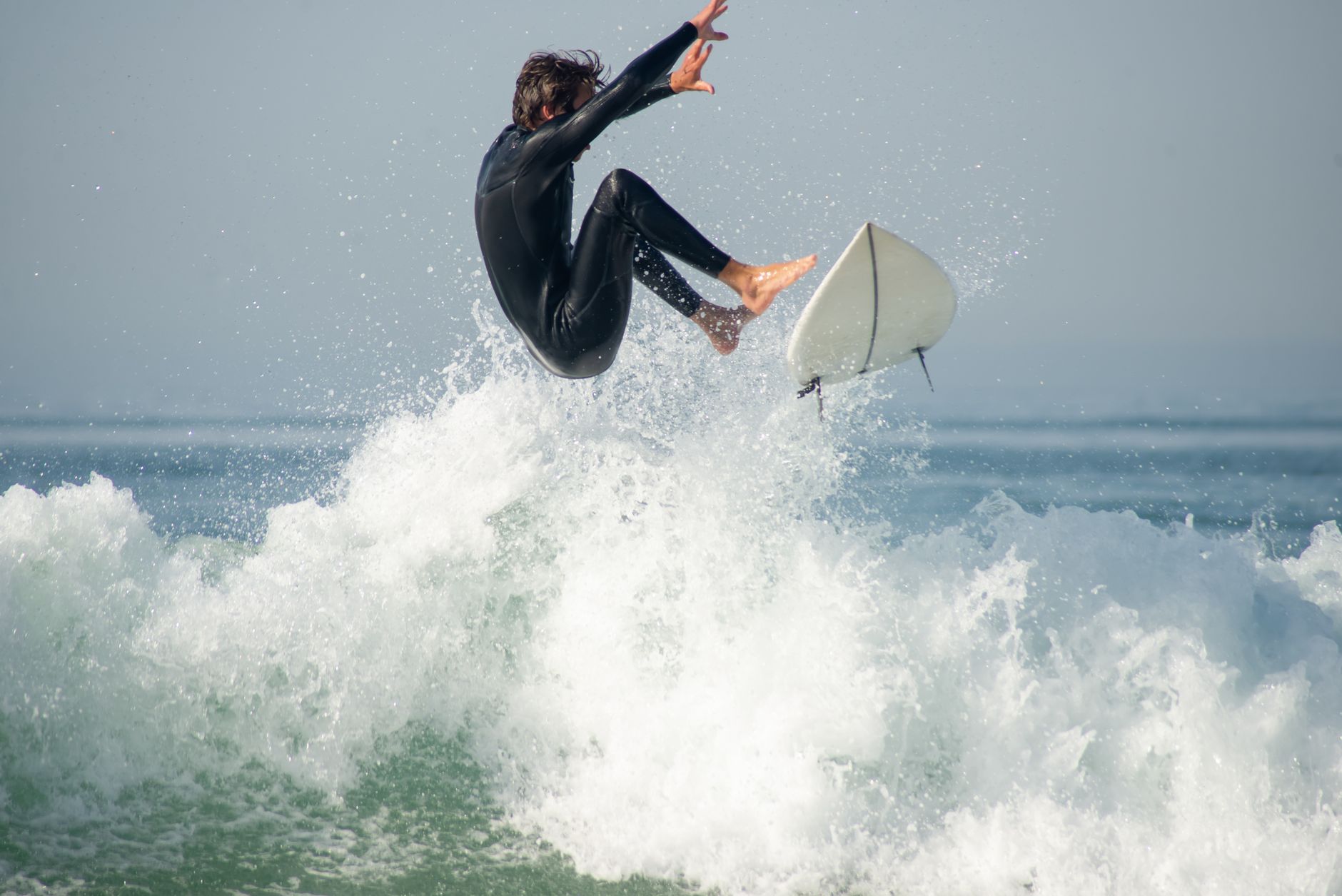 Surfer executing a jump, captured mid-air on the waves of Portugal's coast.