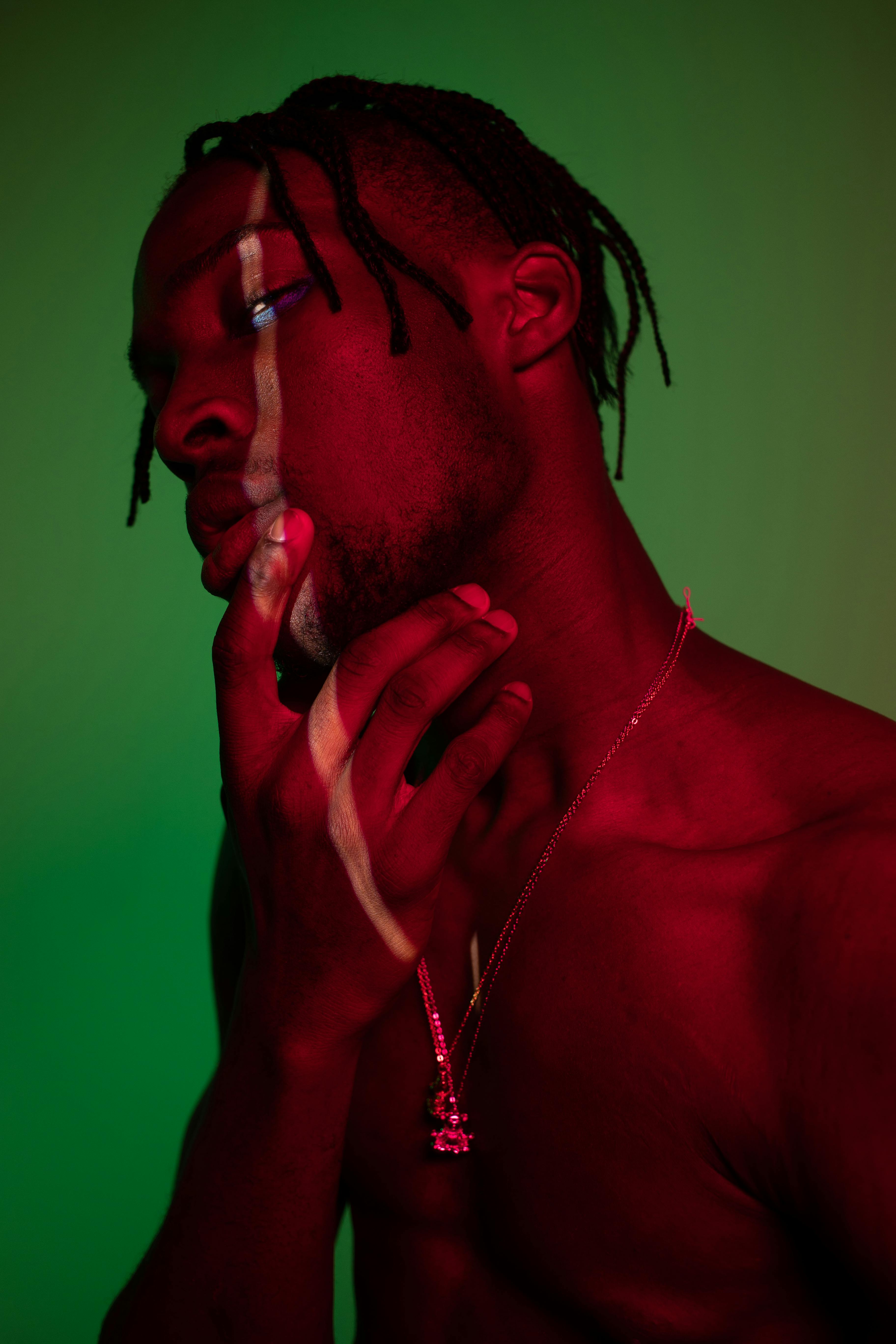 Artistic portrait of a shirtless man with unique lighting effects and contemplative expression.