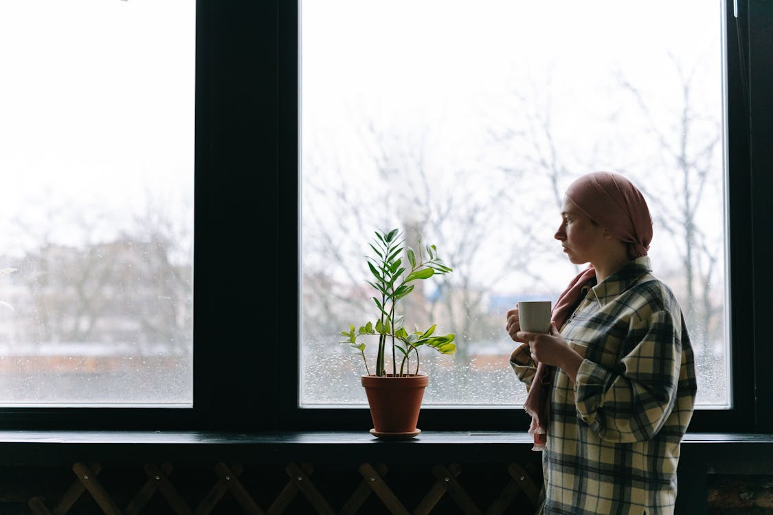 Free A Woman Standing Beside the Glass Window Stock Photo