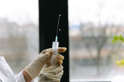 Medical professional holding a syringe, prepared for injection, in a clinical setting.