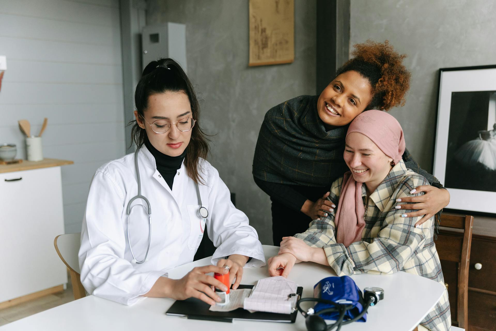 A Medical Professional Sitting Next to Two Women Hugging