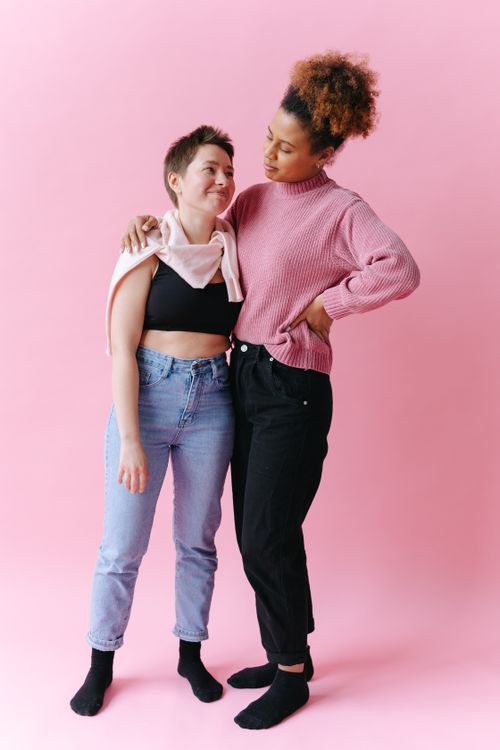 Free Two women embrace and share a moment of affection on a pink backdrop, both smiling. Stock Photo