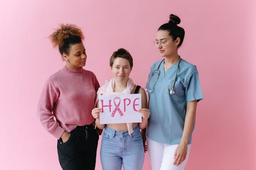 Women Looking at a Woman Holding a Placard with a Pink Ribbon