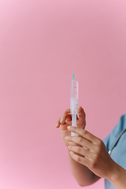 A Close-Up Shot of a Medical Professional Holding a Syringe