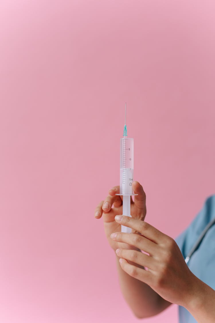 A Close-Up Shot Of A Medical Professional Holding A Syringe