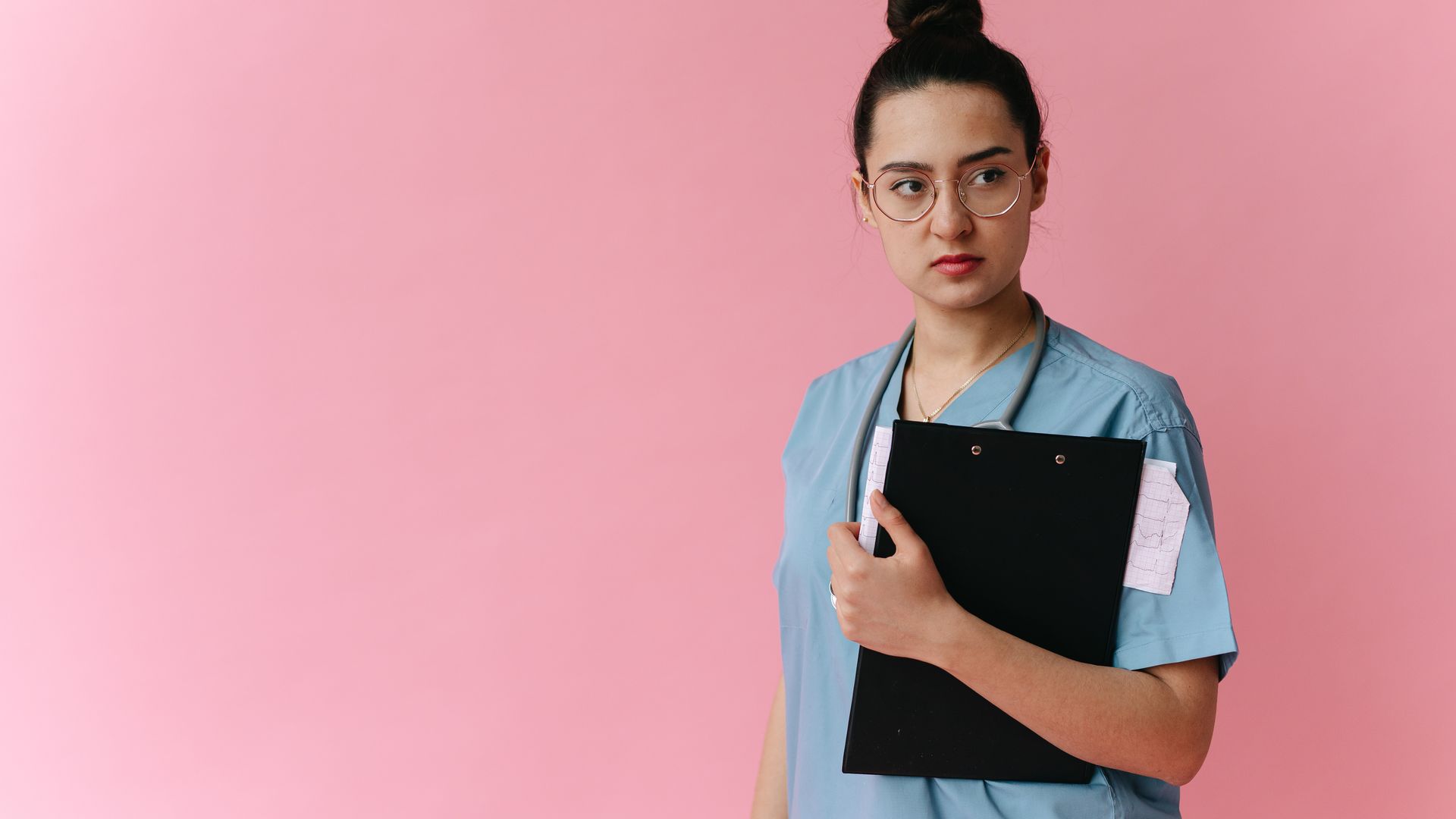 Modafinil for Nurses: A Comprehensive Guide Confident female doctor in scrubs holding a clipboard against a pink background — modafinil for nurses