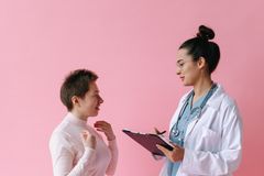 A doctor consults with a patient against a pink background, illustrating healthcare professionalism.
