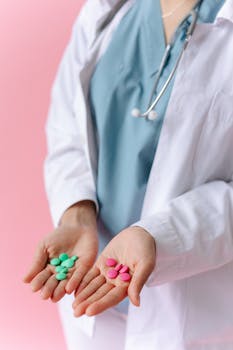 Medical professional displaying colorful pills in hands on a pink background.
