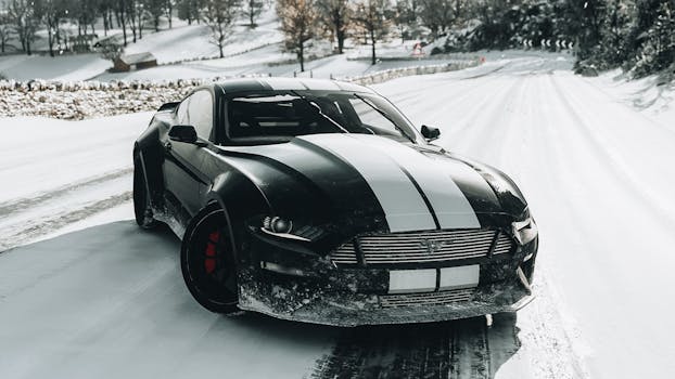 A black Shelby Mustang with white stripes drives on a snowy road, showcasing winter elegance.