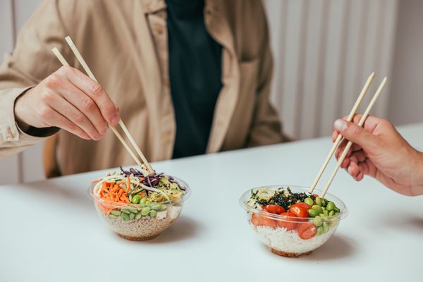 Two people sharing lunch bowls at a table — photo by Cup of Couple on Pexels
