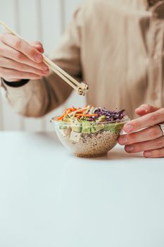 A vibrant mixed vegetable rice bowl being enjoyed with chopsticks, promoting a healthy diet.