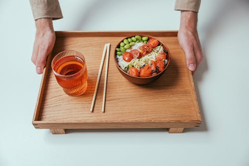 Man Holding Wooden Tray with Drink and Bowl with Asian Food