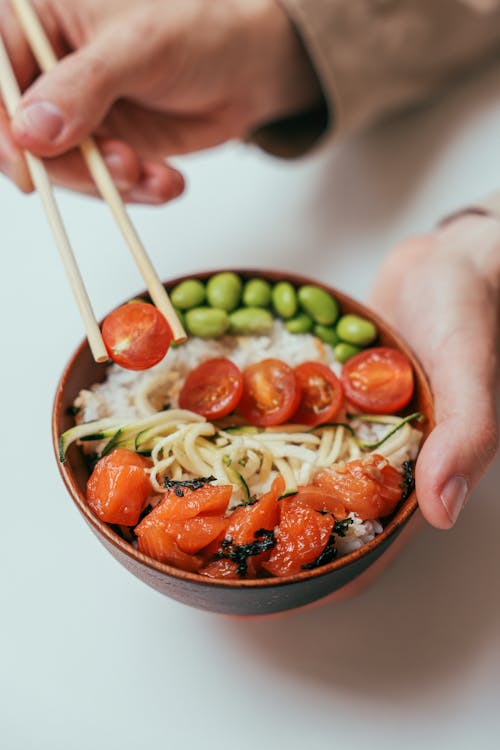 Person Holding a Chopstick and Rice Bowl