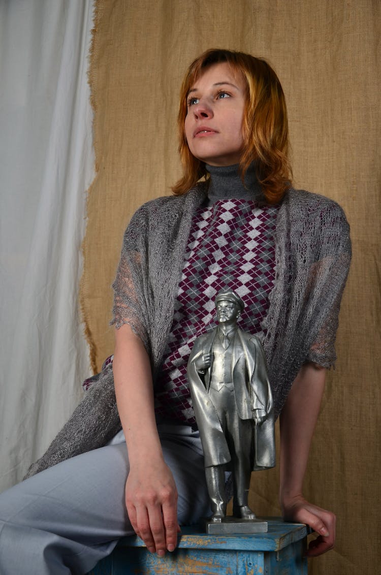 Woman In Grey Knit Sweater Sitting Beside Gray Statue