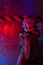 Woman In Spacesuit Sitting With Reflection Of Red light On Background