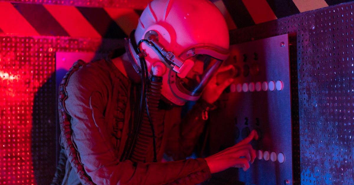 Female astronaut interacts with a control panel in a futuristic spaceship setting.