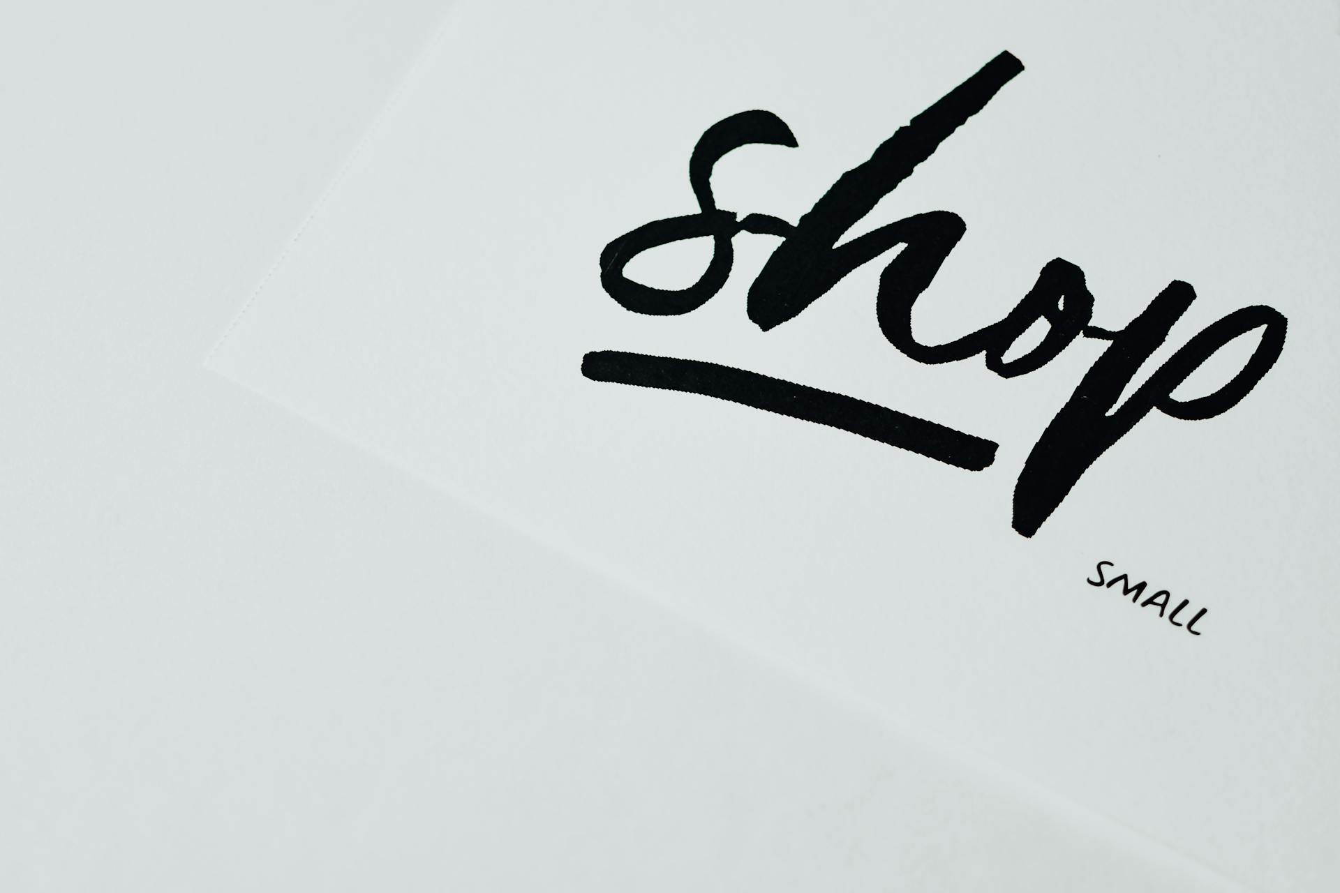 Elegant handwritten 'shop' sign on white background, perfect for retail design.