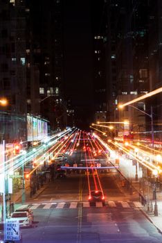 Long exposure shot capturing bustling city street with glowing lights and moving vehicles at night.