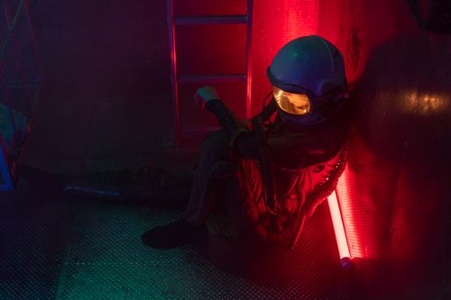Free A worn-out astronaut in a glowing suit rests inside a dimly lit spaceship, capturing the essence of space travel fatigue. Stock Photo