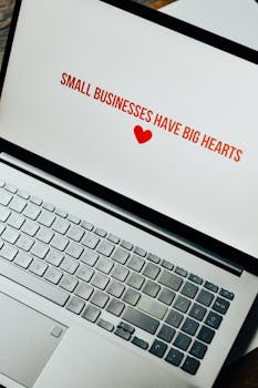 Close-up of laptop displaying 'Small Businesses Have Big Hearts' message with a heart icon.