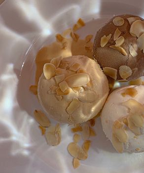 Creamy ice cream scoops topped with almond slices, perfect dessert.