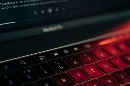 A vibrant close-up of a backlit laptop keyboard with a glowing red hue, showcasing modern technology.