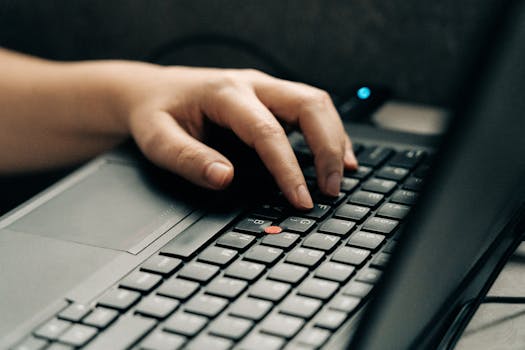 A hand typing on a laptop keyboard. Perfect for technology and business themes.