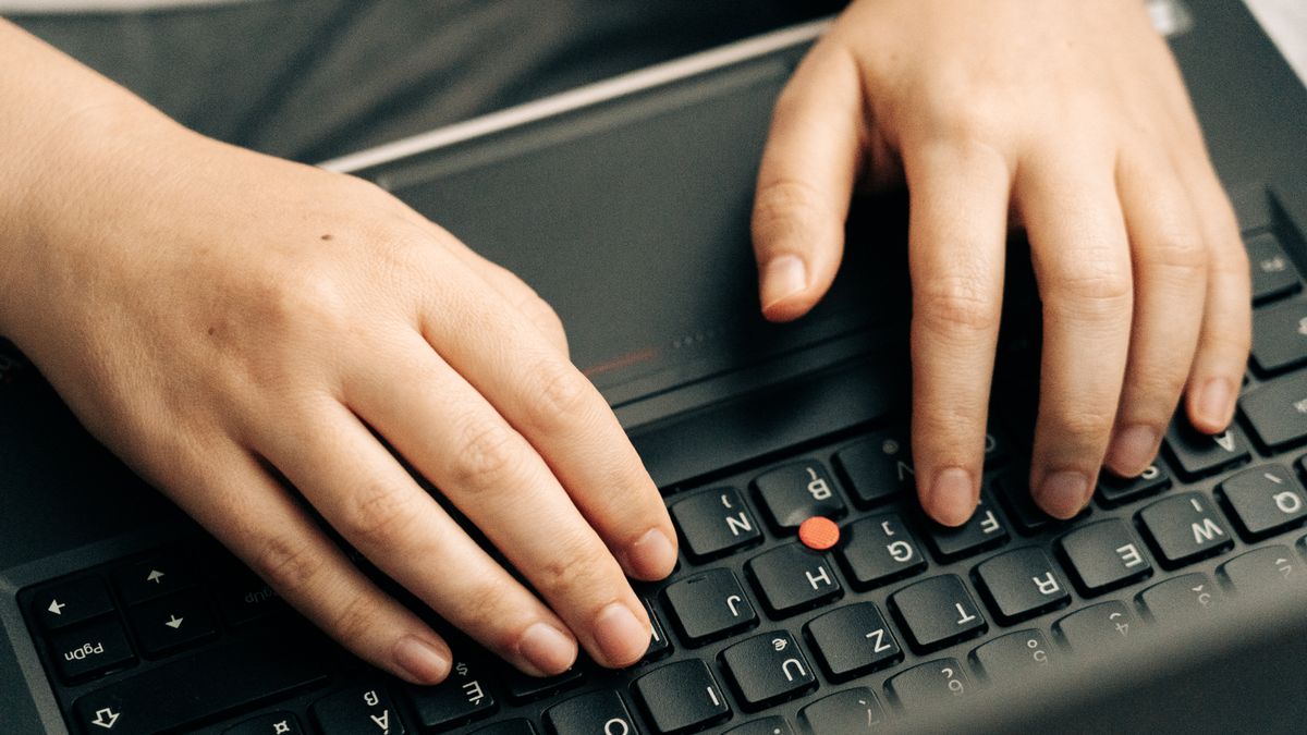 ノートパソコンのキーボードに手を置いて作業している手元のイメージ