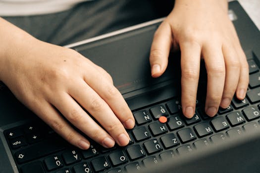 Close-up of hands typing on a black laptop's keyboard emphasizing productivity.