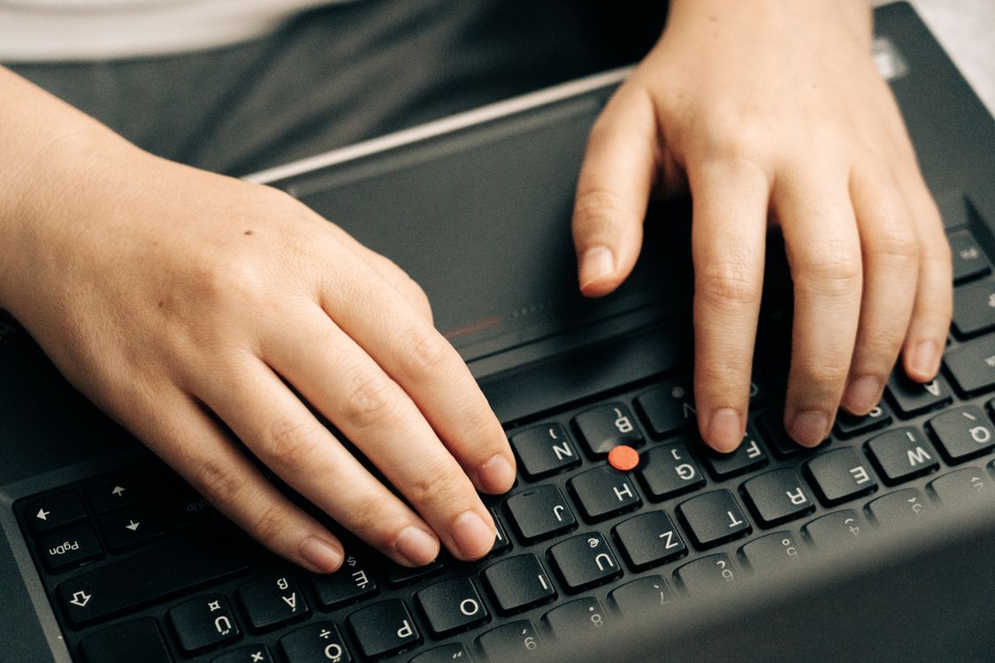 Hands typing on a laptop keyboard working on a document or essay