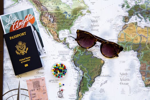 Flat lay of travel essentials with a world map, passport, and sunglasses.