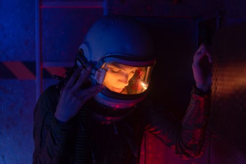 Free A futuristic female astronaut explores space in a glowing helmet, embodying modern sci-fi and technology. Stock Photo