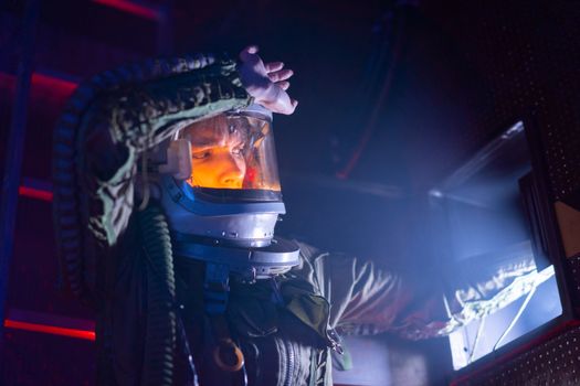 A woman in a spacesuit explores a futuristic spacecraft interior with dramatic lighting.
