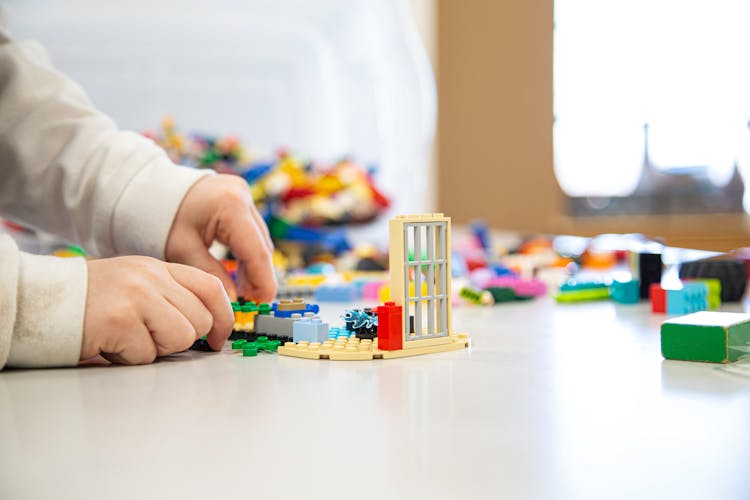 Person Playing Lego Blocks On Table