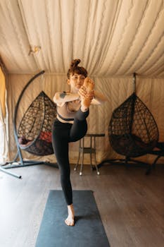 A woman in sportswear practices yoga indoors, focusing on flexibility and relaxation.
