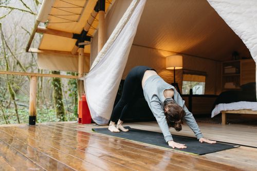 Free A woman practicing yoga outdoors in a glamping tent, promoting wellness and self-care. Stock Photo