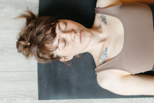 Peaceful woman in tank top resting with eyes closed, showcasing tattoos